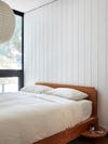 simple wood bed against white paneled wall