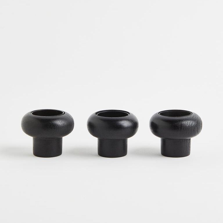 A row of three black wooden candle holders against a white background.