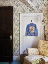 Kid's room with floral wallpaper and denim jacket hanging on door
