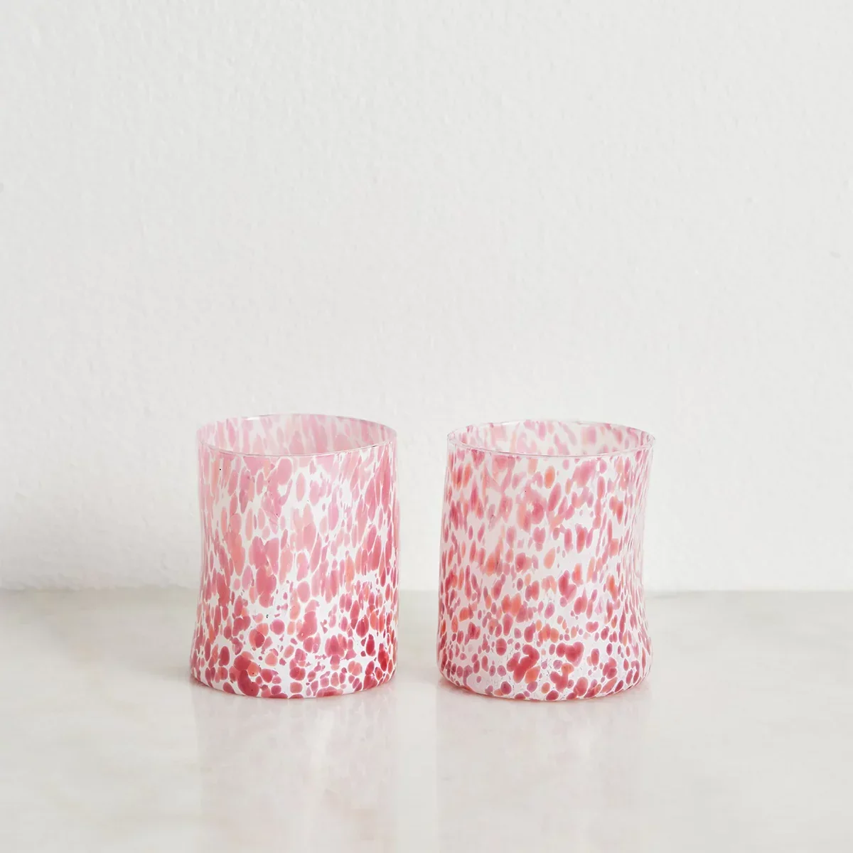 Handblown glasses featuring flecks of soft pink against a white background.