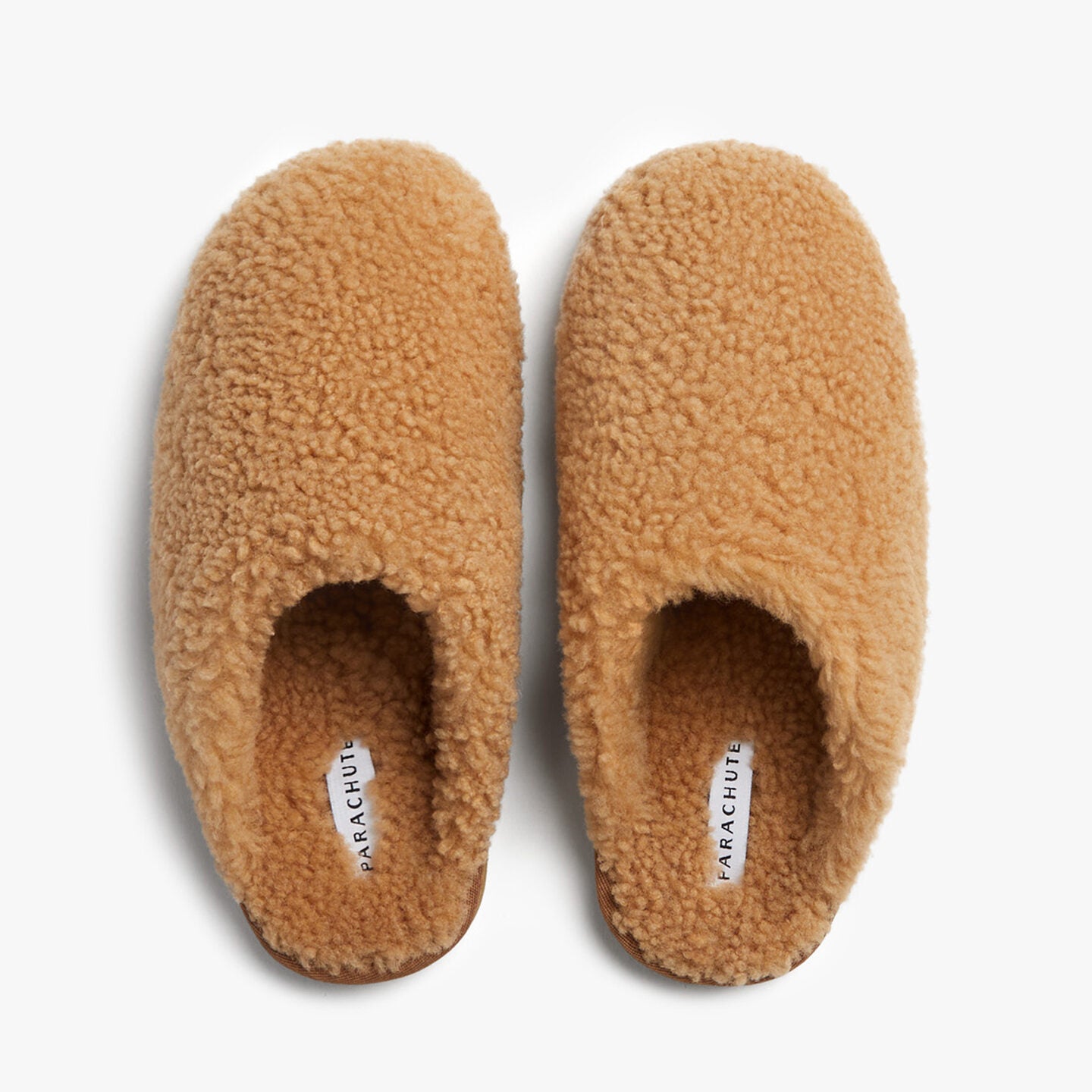 Light brown fluffy wool clogs against a white background.