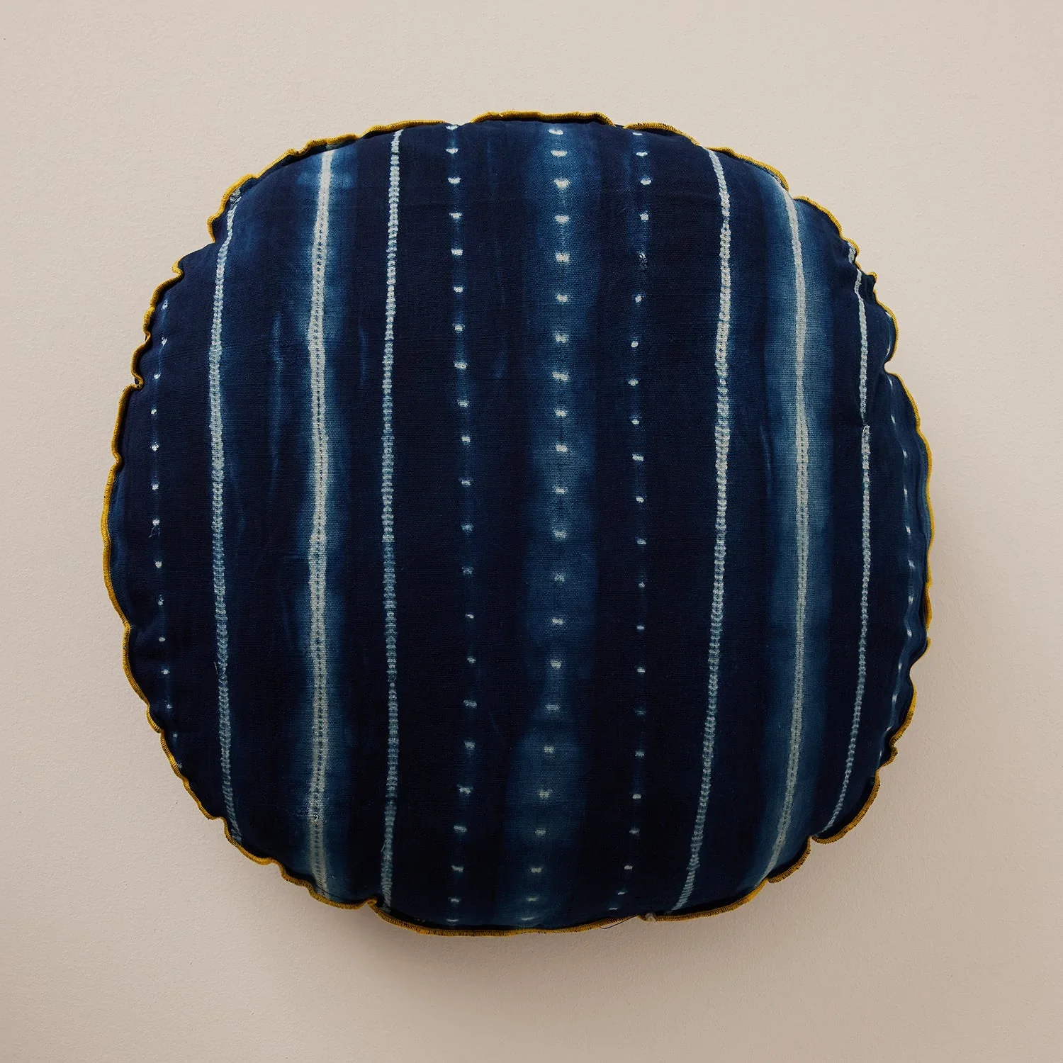 Striped midnight blue floor pillow against a cream background.