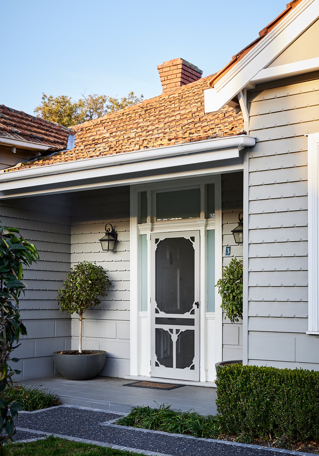 Front door entrance of Edwardian home in Melbourne with potted trees outside
