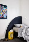 quarter-circle fabric headboard behind small boys bed and corn night stand