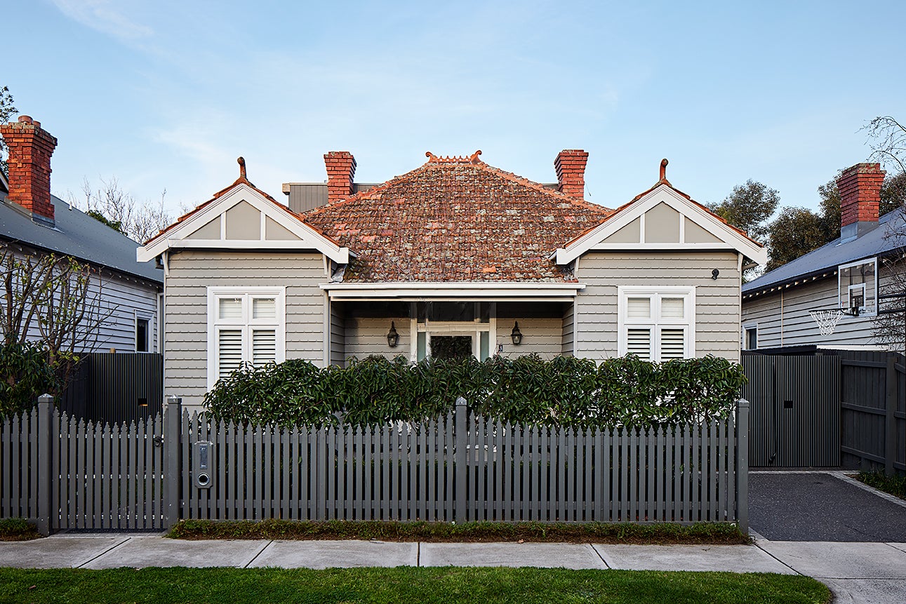 shot of double-fronted edwardian home with terracotta shingles from the road behind picket fence