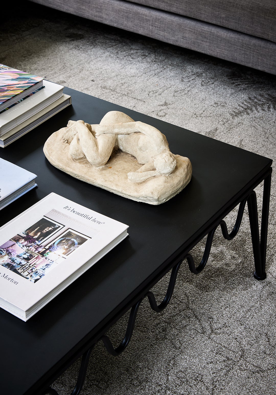 Black wavy coffee table with books and sculpture on top 