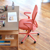 The coral-colored Verve Chair styled inside of an airy home-office space.