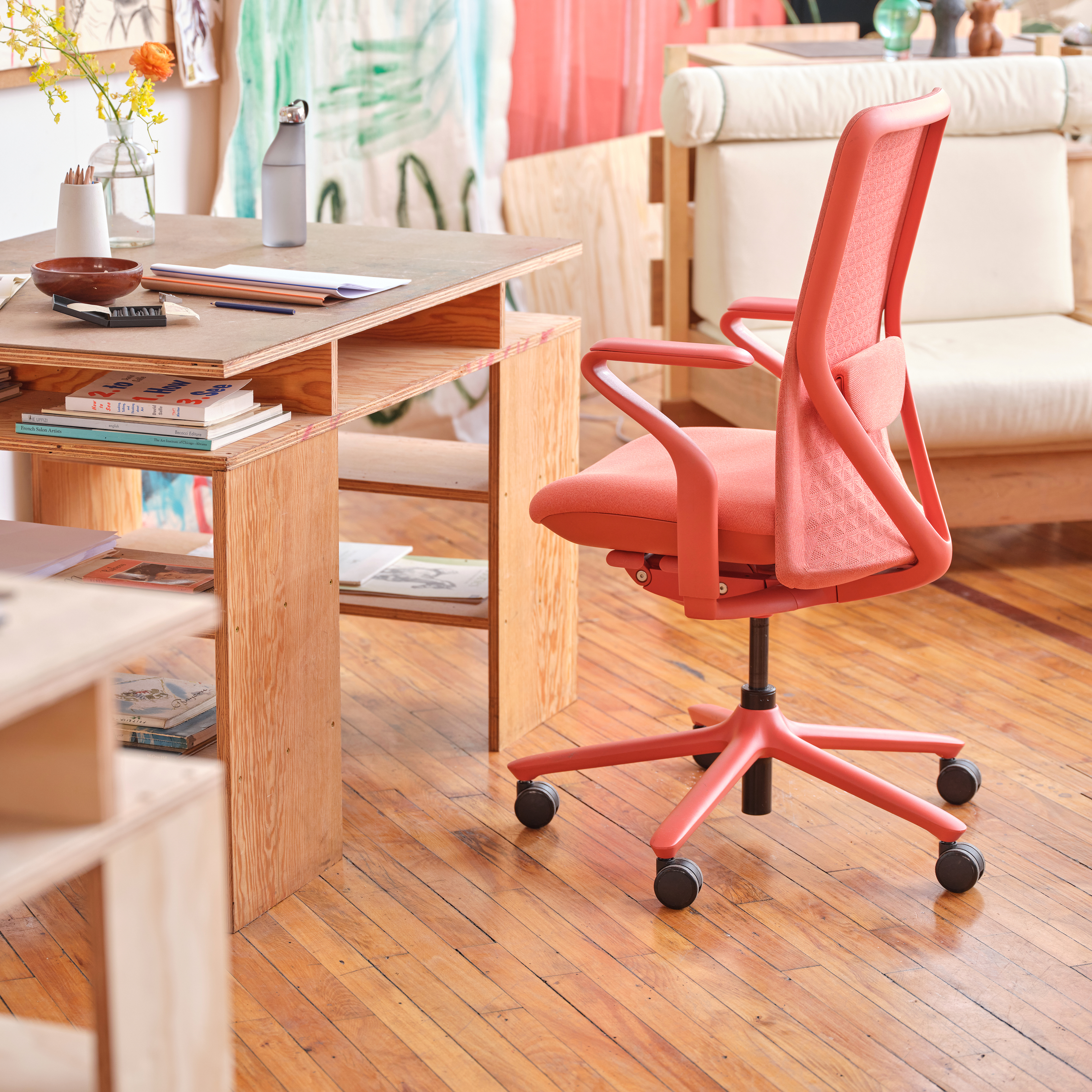 The back of a coral-colored office chair inside of an airy home-office space.
