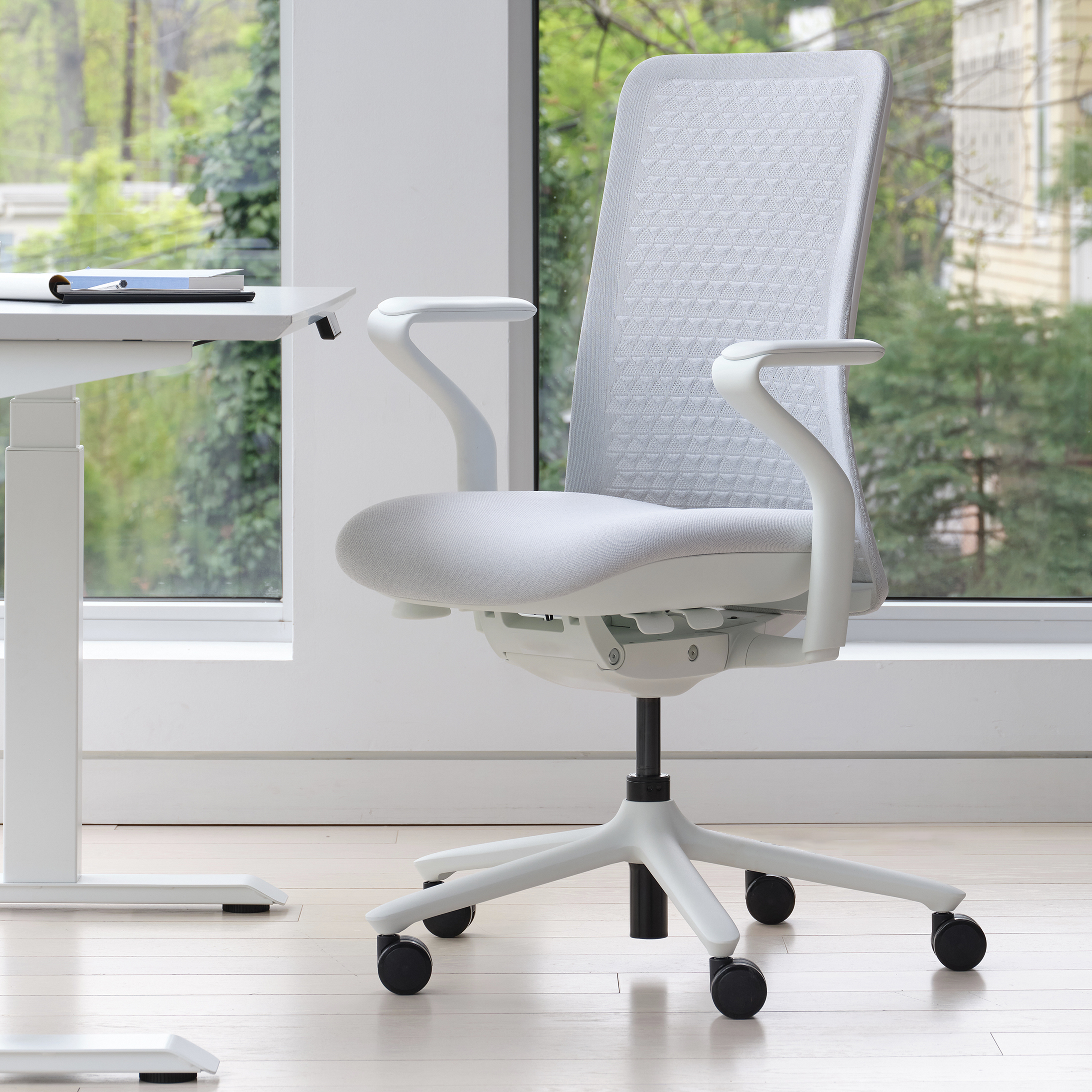 The front of a light grey-colored office chair inside a home office.