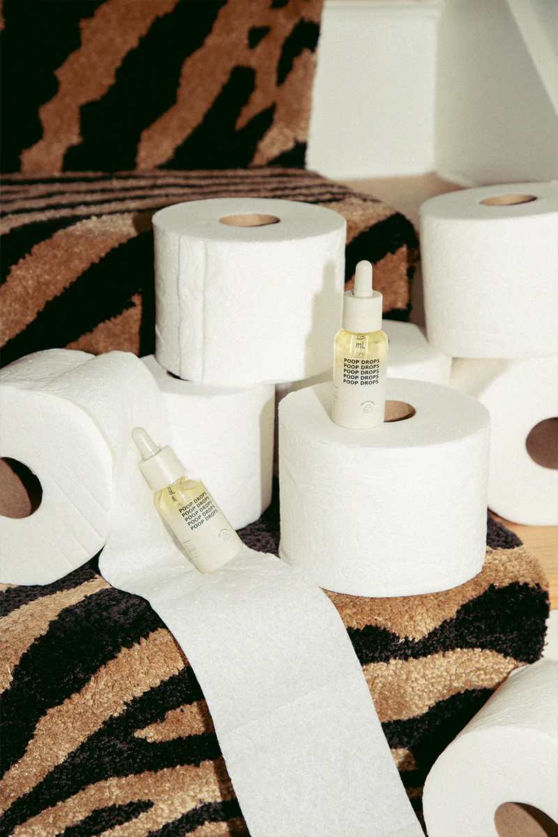 DedCool's Poop Drops sitting on top of a group of toilet paper rolls.