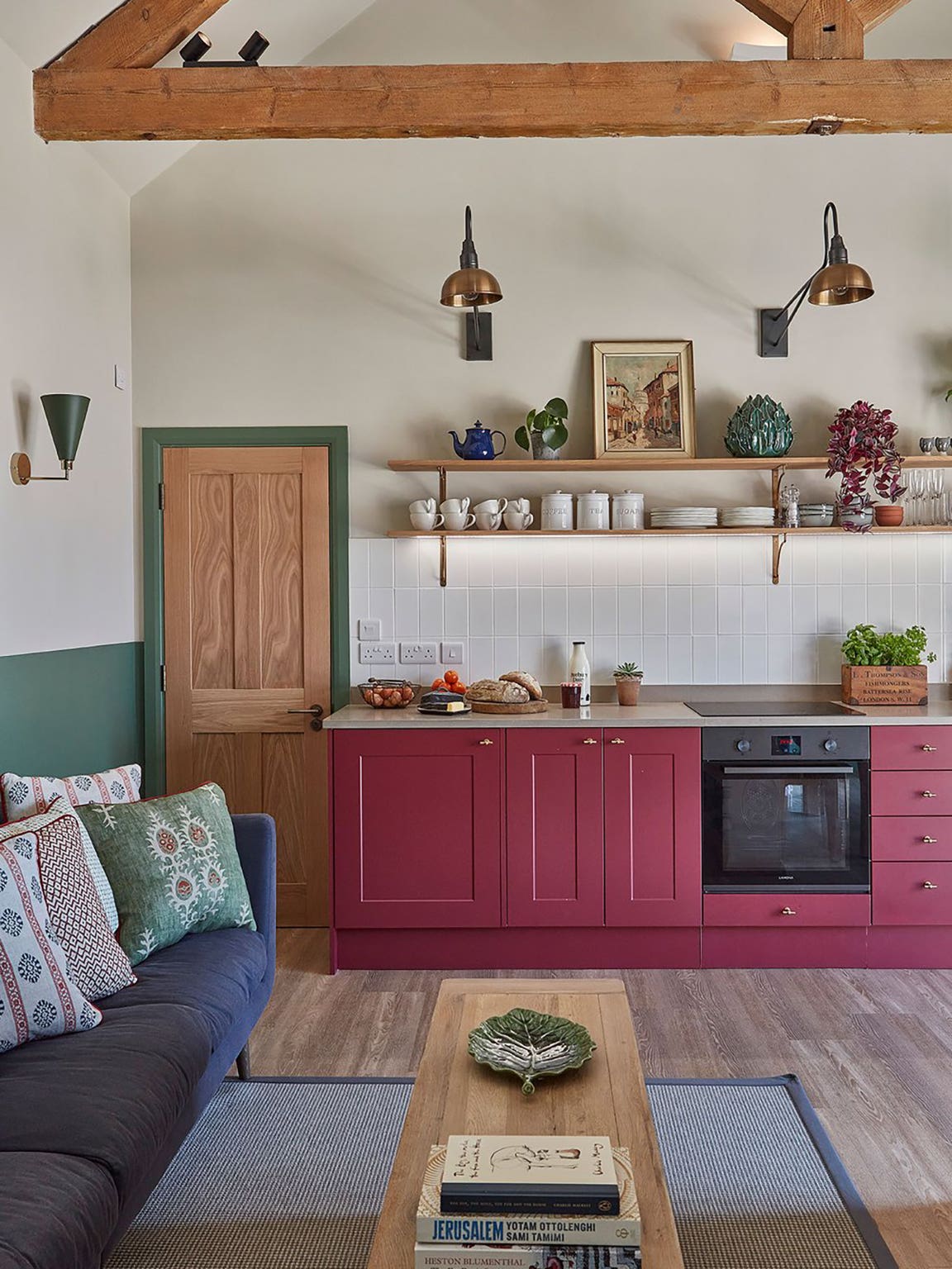 open kitchen with red cabinets and floating shelves and green painted trim
