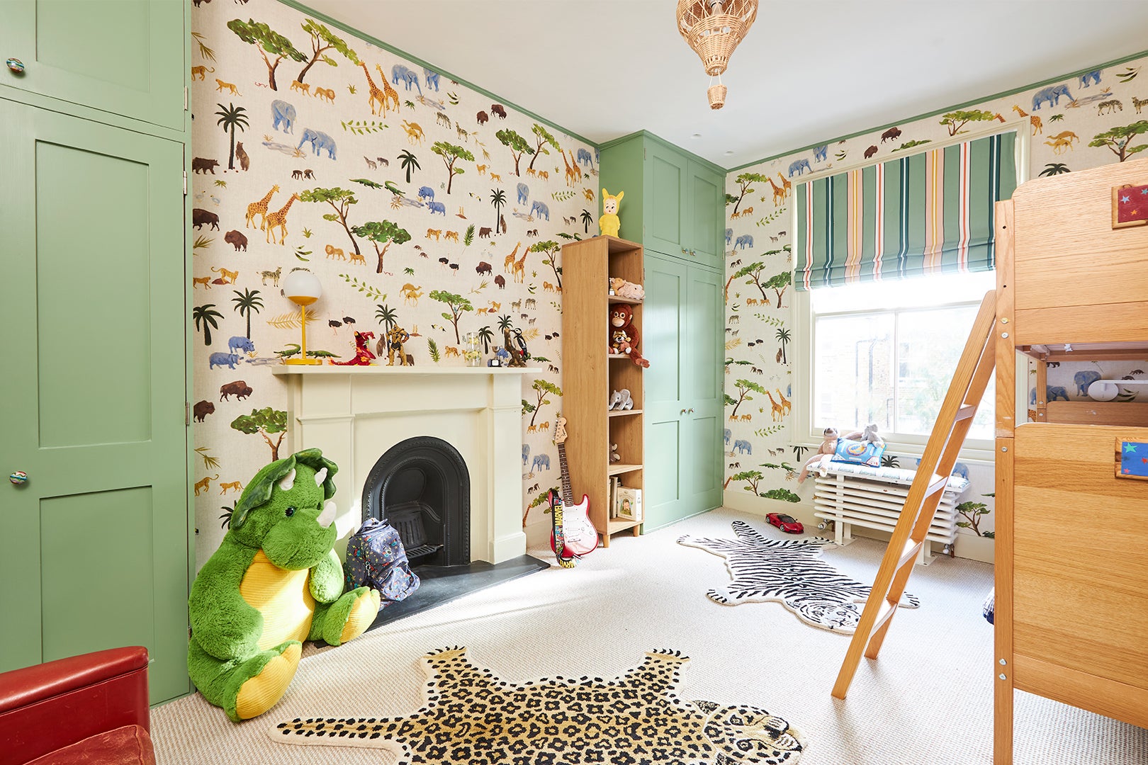 kid's room with safari wallpaper and green cabinets
