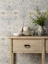 Floral wallpaper behind wood console table decorated with tableware and vase of flowers
