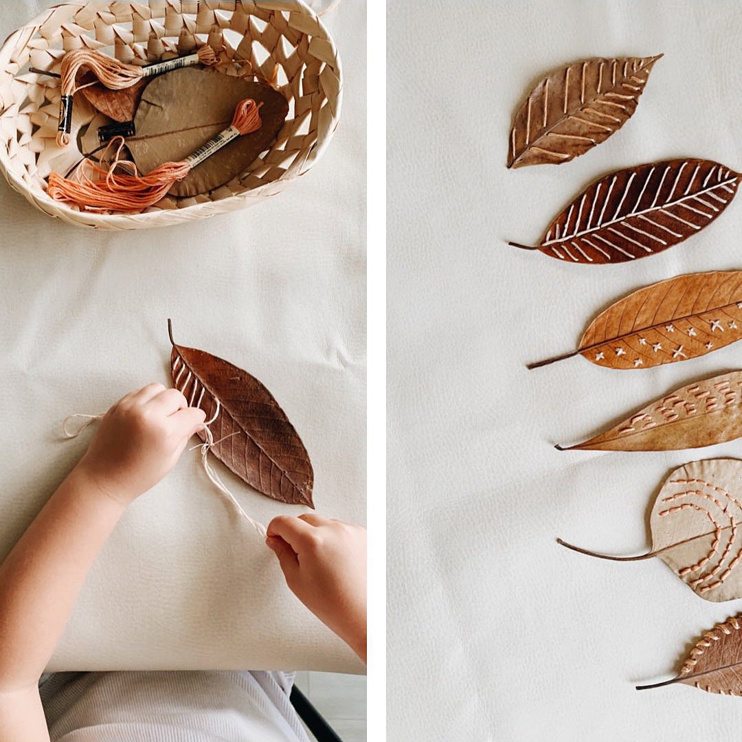 child sewing patterns into fallen leaves