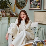Drew Barrymore sitting on a cream-colored boucle chair