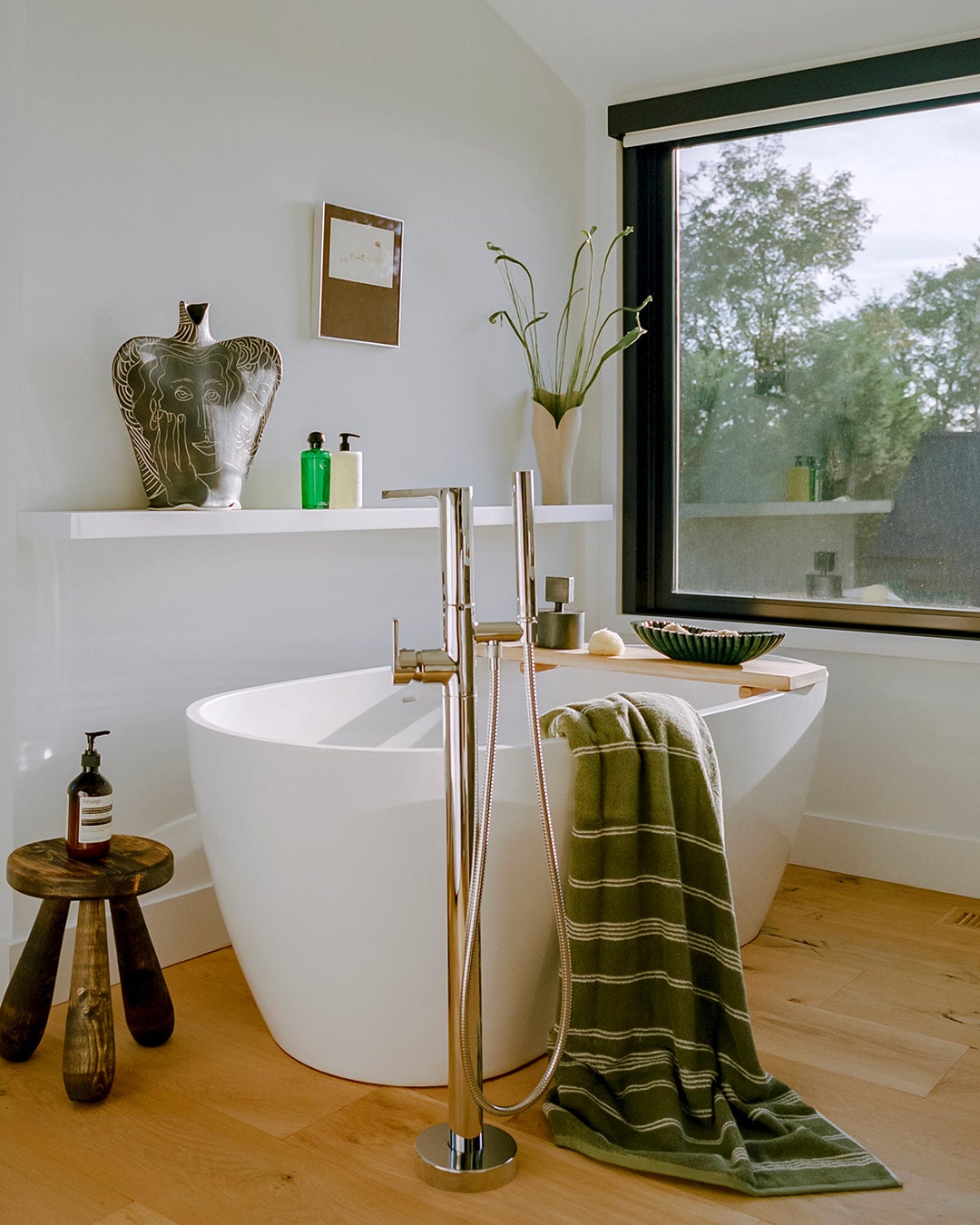 Egg-shaped bathtub with green striped towel hanging over