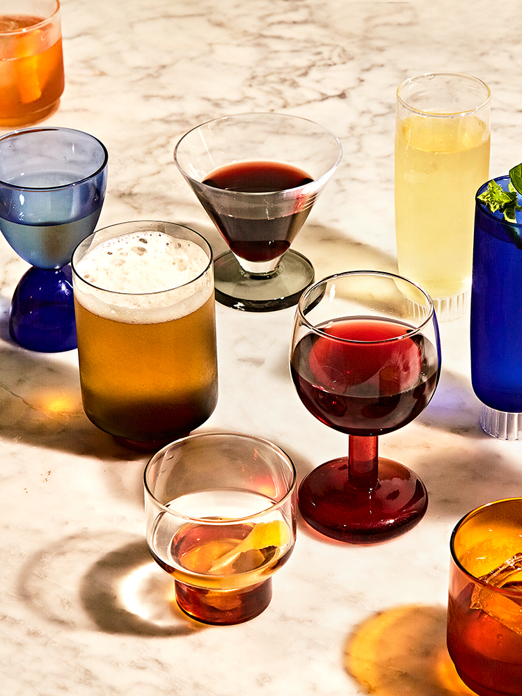 Assorted glassware filled with various drinks styled on a marble tabletop.