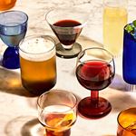 Assorted glassware filled with various drinks styled on a marble tabletop.