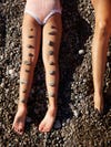 shells lined up on kids' legs on beach