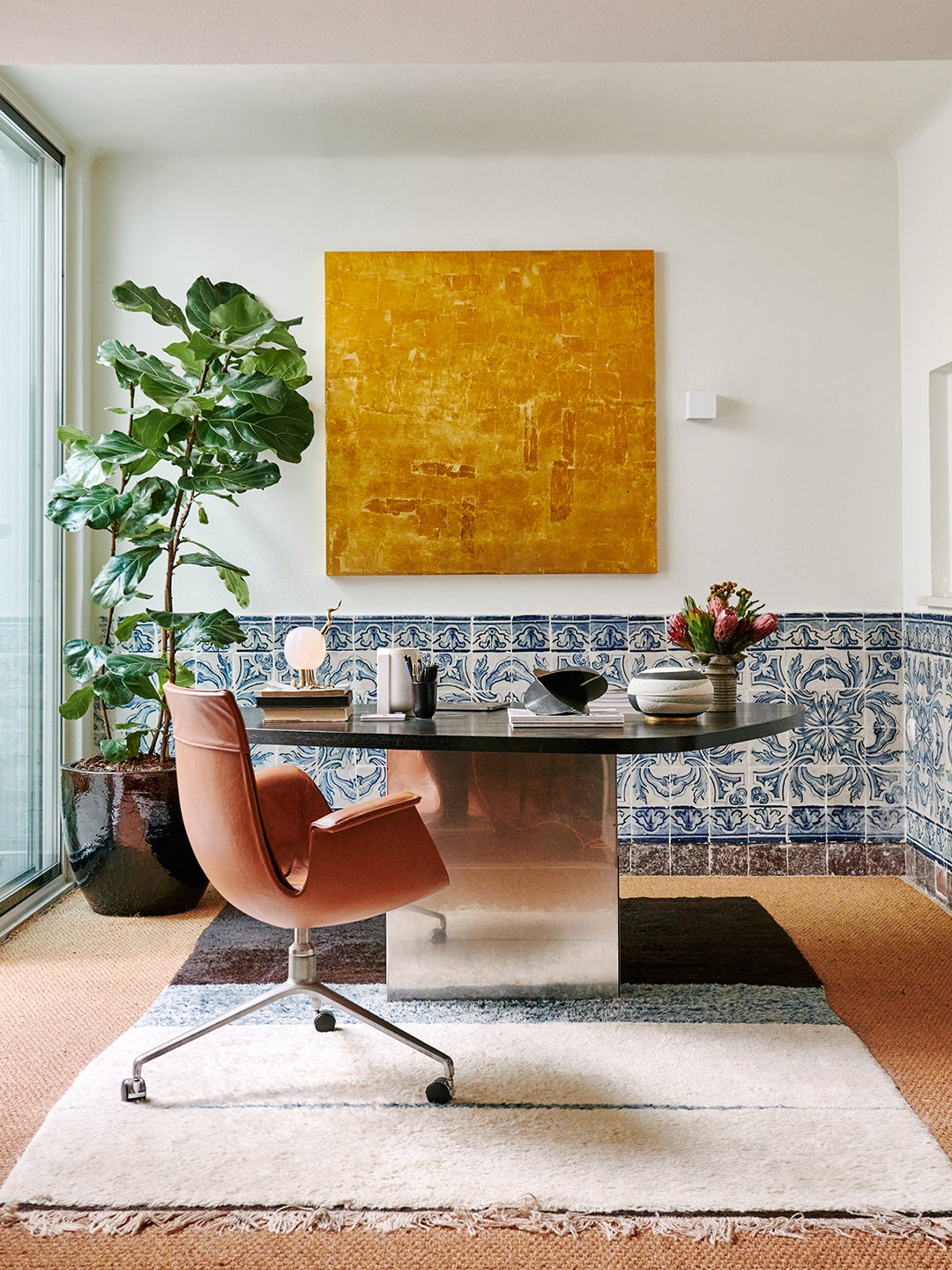 office with a tulip chair and a gold painting hanging behind a desk