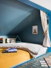 Sleeping nook painted blue with yello bedding