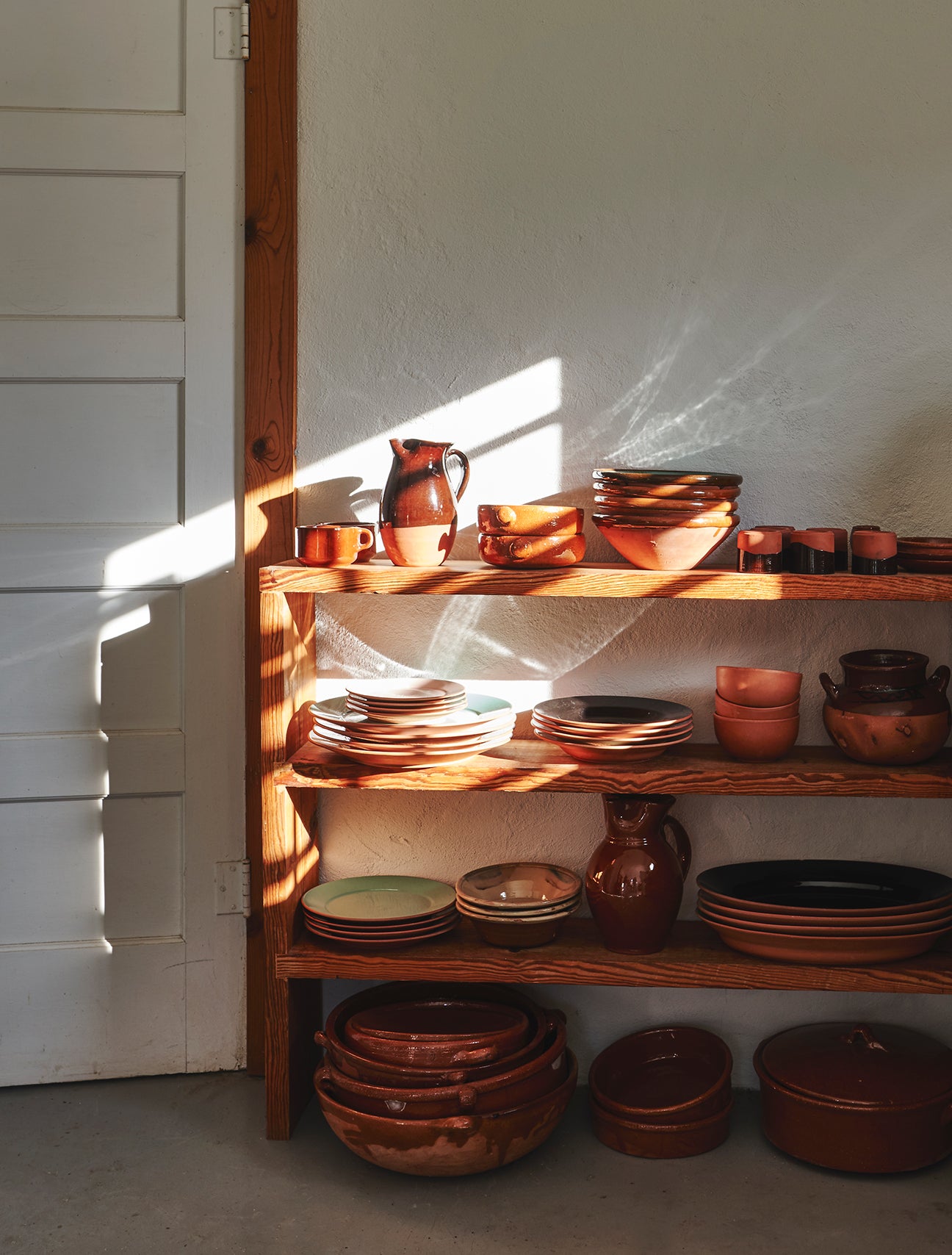 low wood shelving unit with pottery