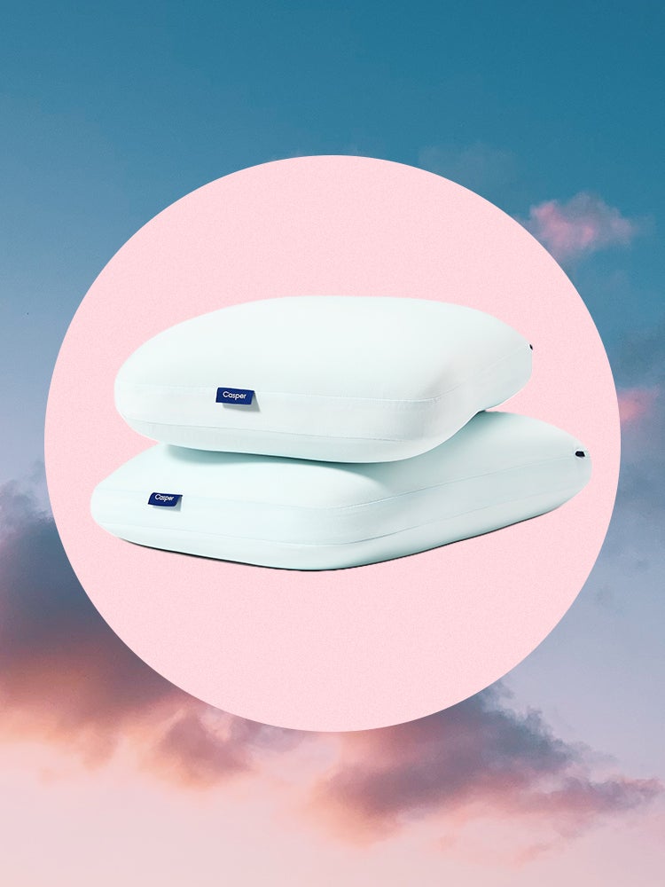 Two of Casper's hybrid pillows with cooling, blue covers siloed on a pink circle and sunset sky
