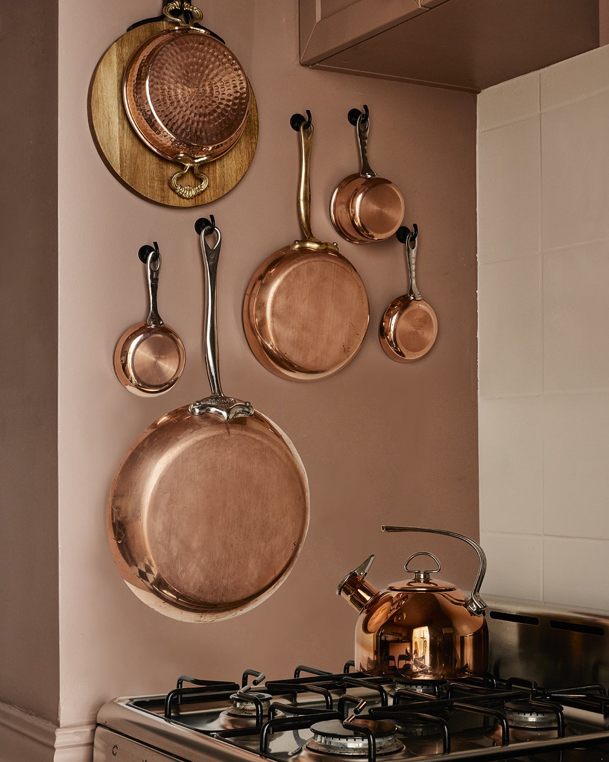pink kitchen with copper pots on wall
