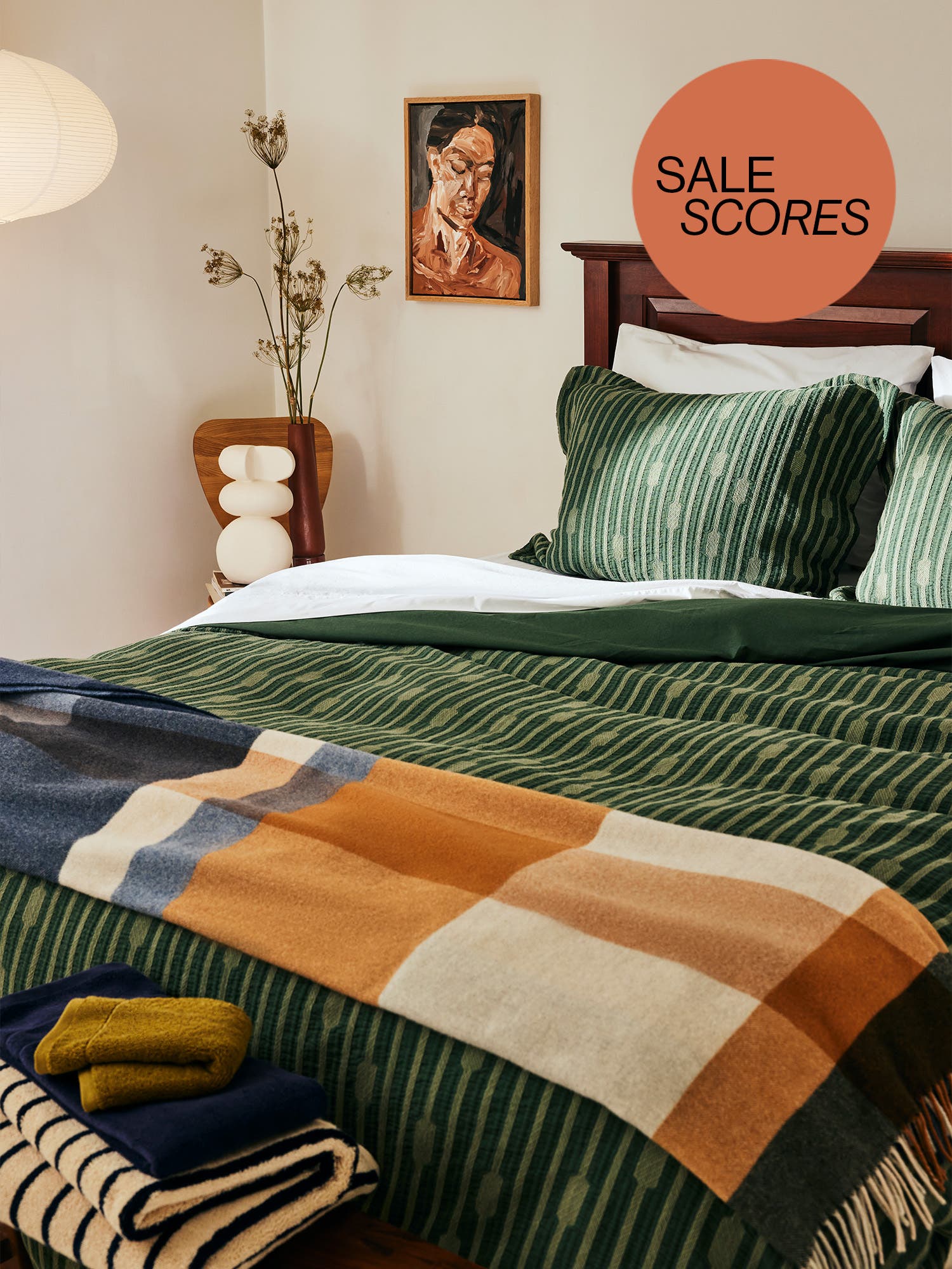 Green bed with plaid balnket draped at thet foot and Domino commerce sale scores button