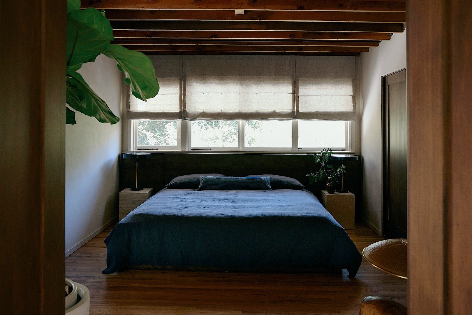 Bedroom with dark blue bedding and window behind bed