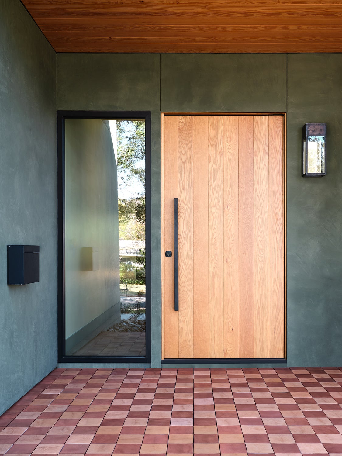 wood front door, green stucco exterior