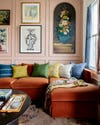 Living room with pink wall and burnt orange sofa