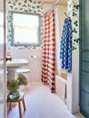 wallpapered kids' bathroom with green built-in cabinets