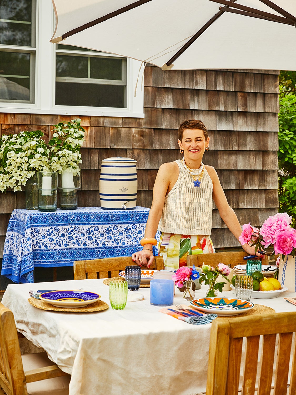 Woman at outdoor dining table, setting up for dinner