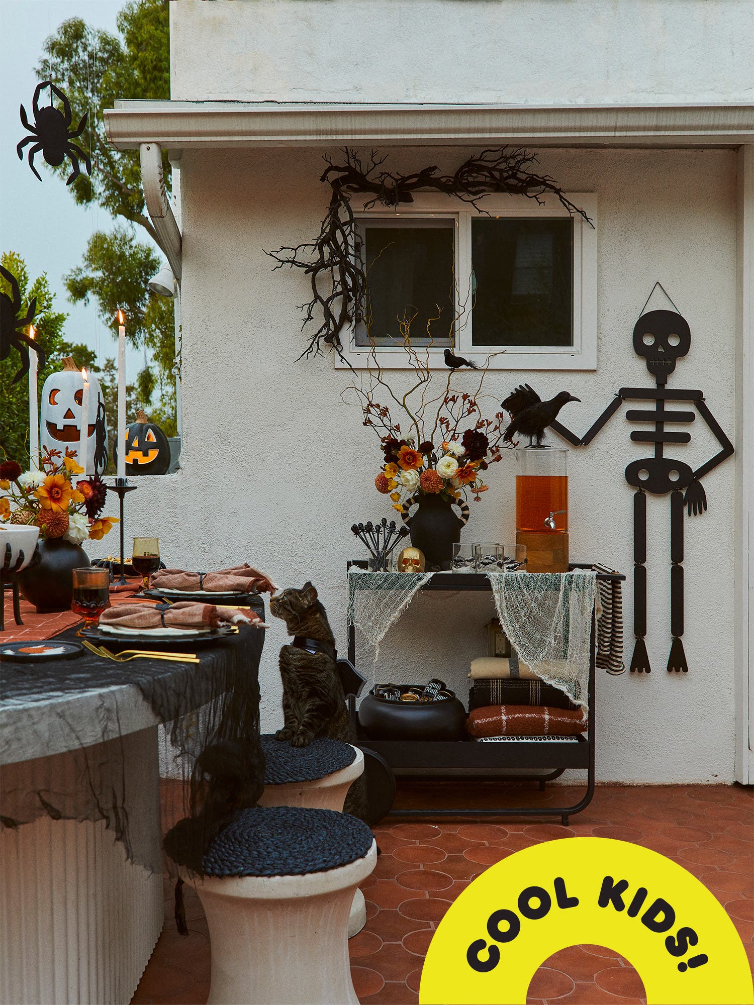 Halloween decor outside with black hanging skeleton and cat dressed with wings from Emily Henderson