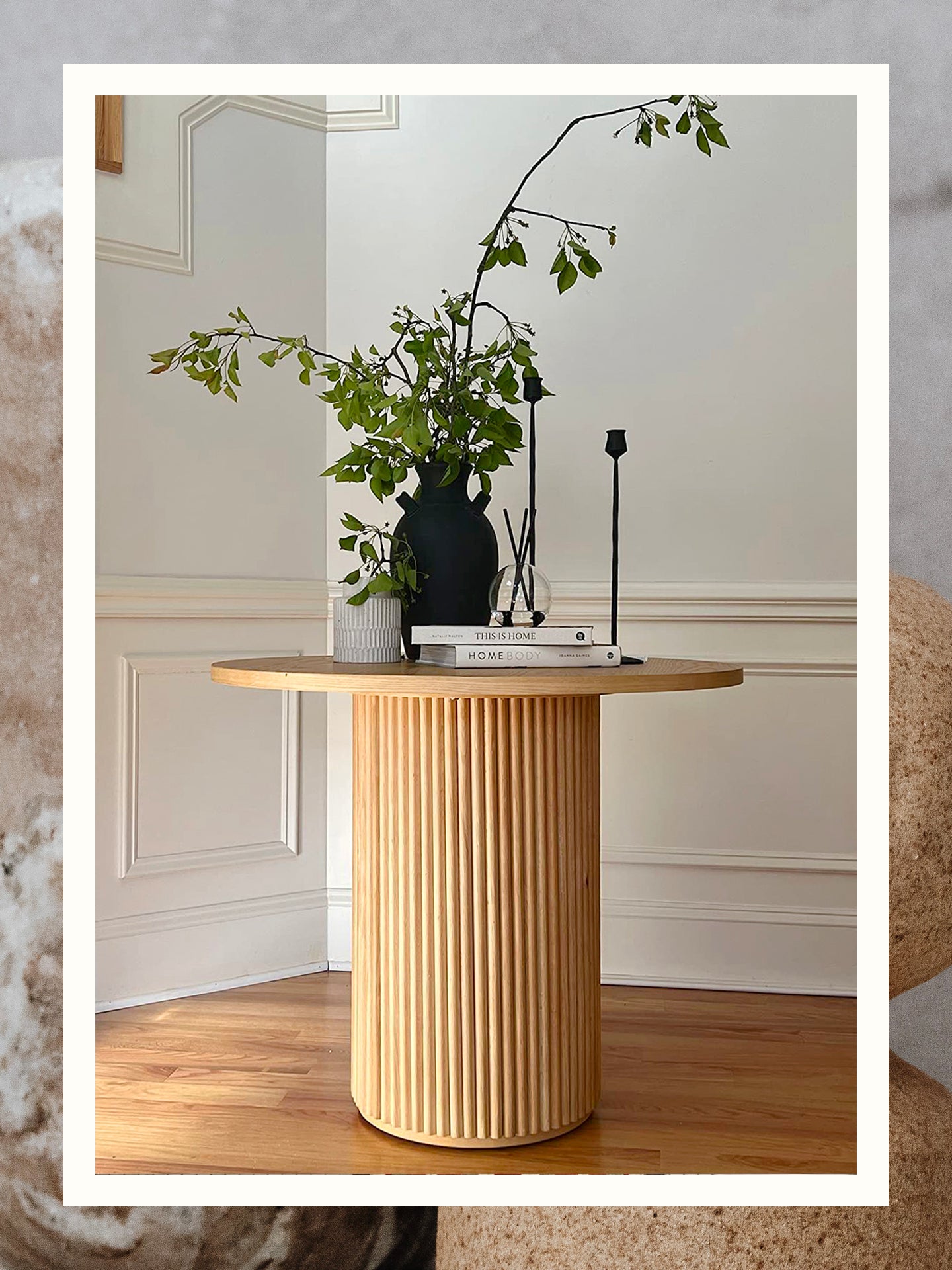 Round wood fluted table from Amazon in entryway topped with black vase and stack of books taken by reviewer