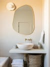 Bathroom with bowl sink and curvy mirror