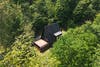 A-frame cabin painted black, pictured from above. 