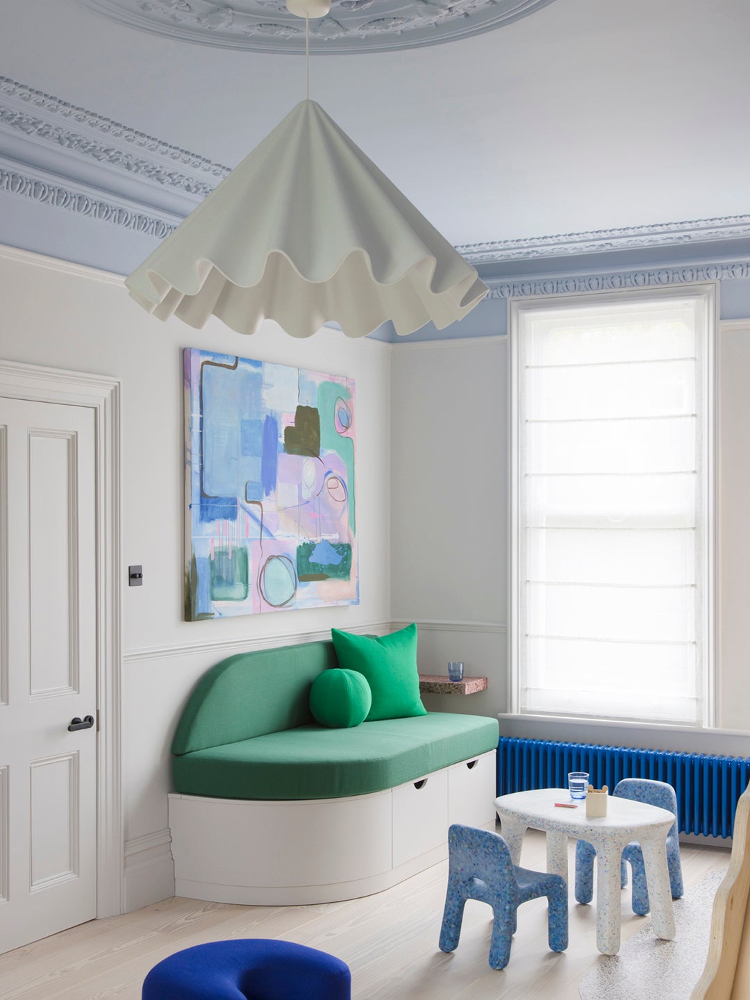 Kids' room with frilly white pendant lamp and green banquette sofa.