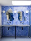 Blue tiled bathroom with puddle-shaped mirrors.
