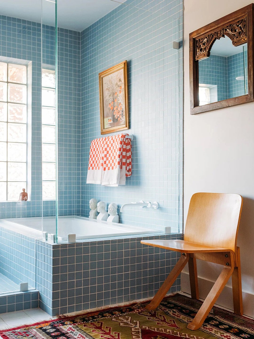 Bathroom with powder blue tile, oriental rug, and wood vintage chair.