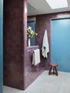 Blue and purple tiled bathroom with wood stool.