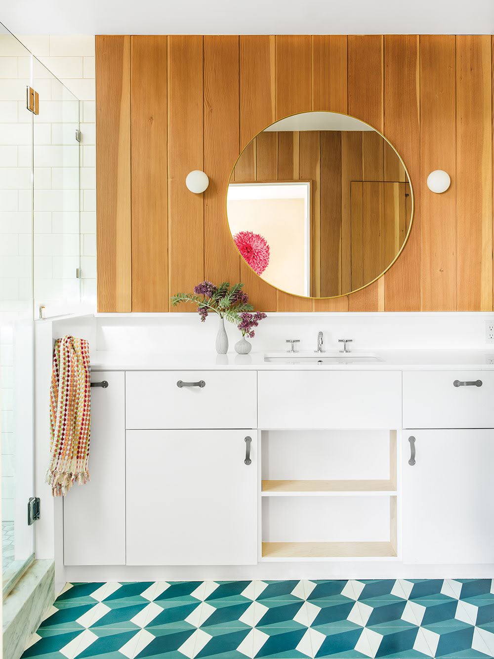 Bathroom with round mirror, wood paneled walls, and geometric tile.