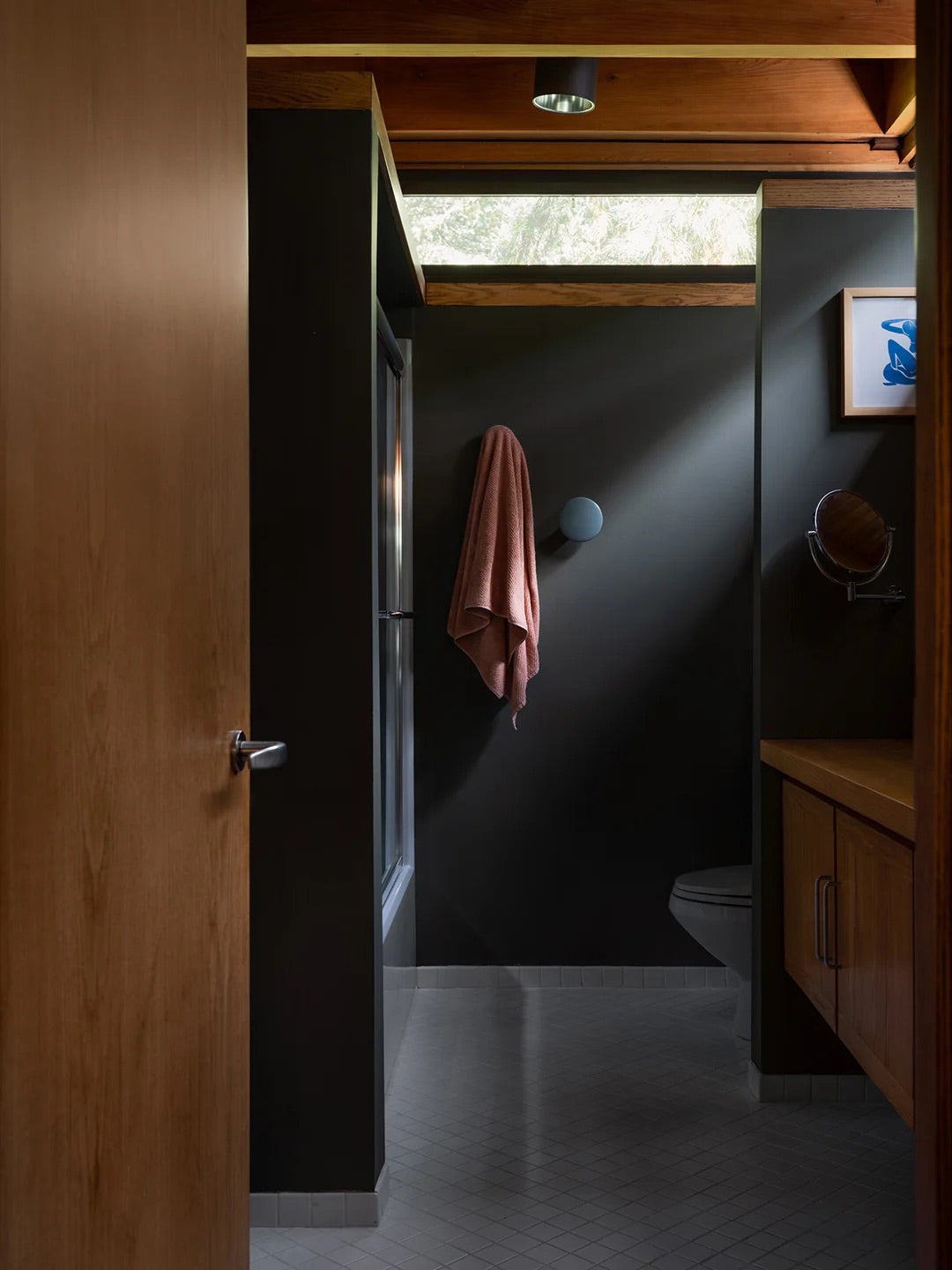 Bathroom painted black with oak wood door. 