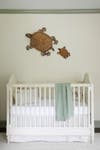 White crib with turtle figurines on wall.