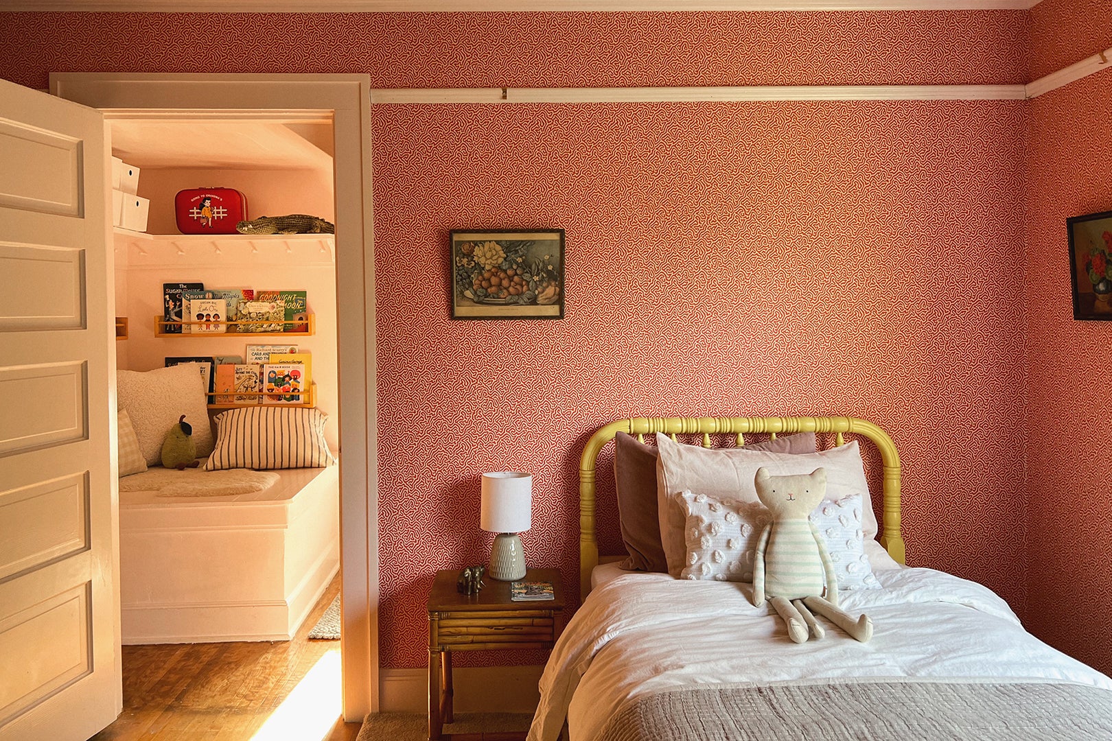 Kids room with yellow bed and red patterned wallpaper. 