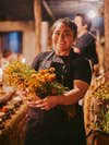 Oaxacan chef Thalia Barrios in her kitchen at nighttime holding flowers.