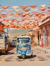 Small blue truck under colorful street flags in TeotitlÃ¡n del Valle near Oaxaca, Mexico.