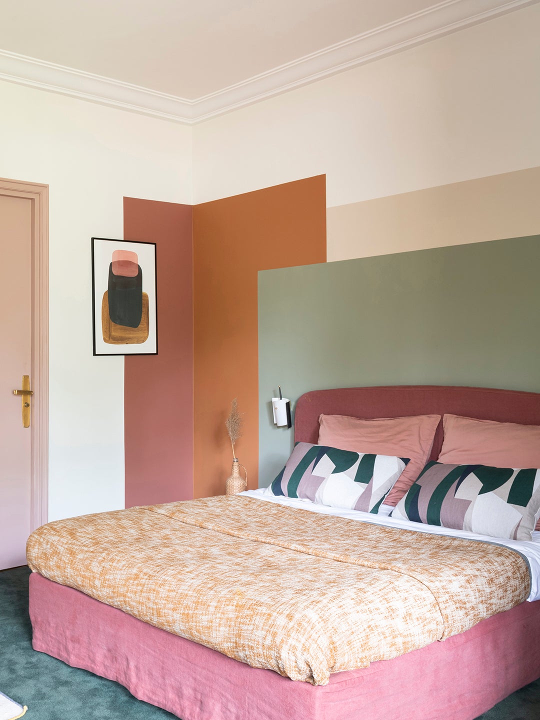 Bedroom with colorblocked wall in terracotta, sage, and beige. 