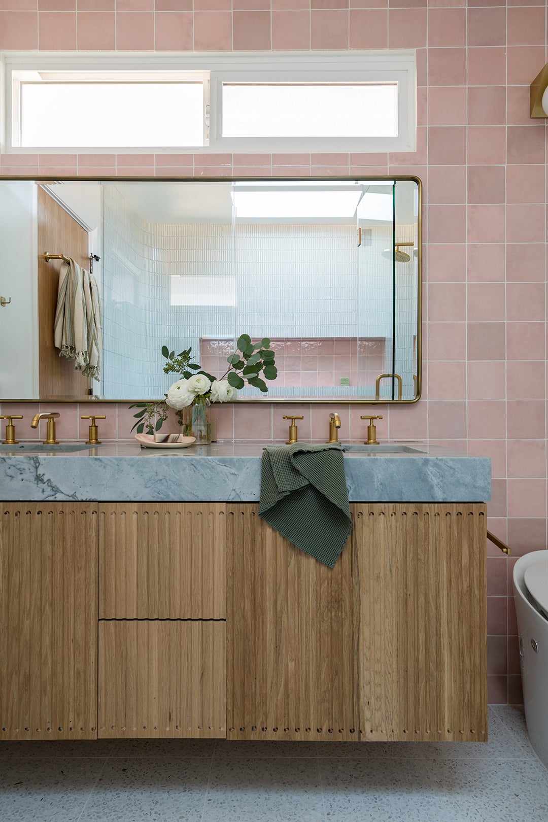 wood vanity with pink tile backsplash